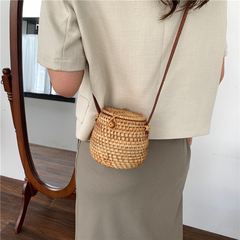 Woman wearing Rattan Barrel Bag with PU leather crossbody strap, adding a natural boho-chic touch to her beige and olive green outfit.