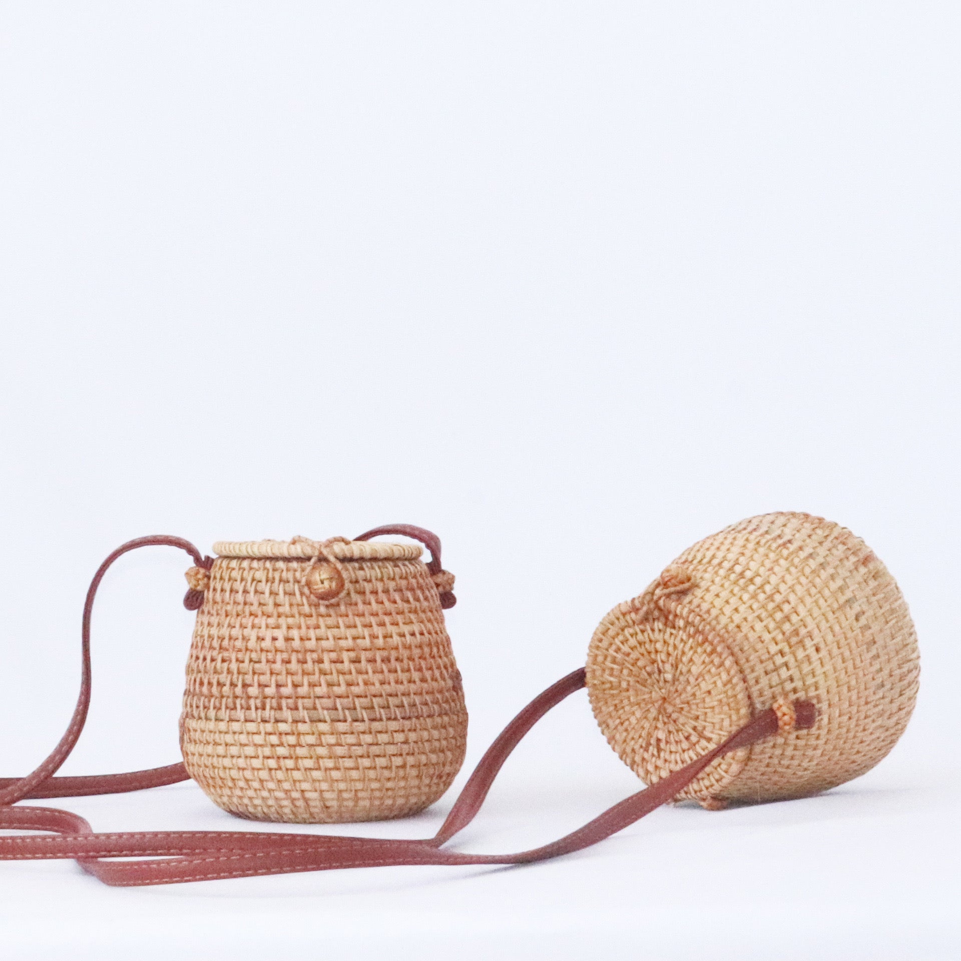 Handwoven rattan barrel bag with PU leather crossbody strap, eco-friendly and boho-chic, ideal for daily use or special occasions.