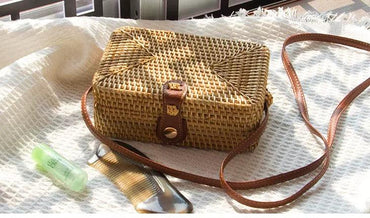 Rattan Box Bag with natural woven design and leather strap, perfect for casual outings, shown on a white textured background with accessories